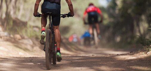 Fototapeta na wymiar Athletes mountain biking on forest trail, mountain bike race