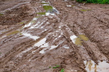 dirty clay mud crossroads with puddles and tire tracks - close-up with selective focus and linear...
