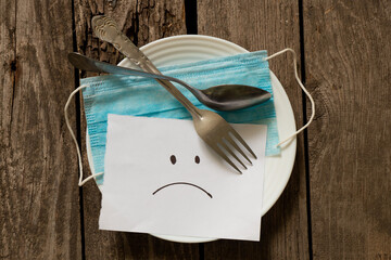 medical mask sad emoticon painted on white paper on a wooden table