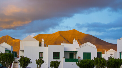 Casas típicas blancas de Lanzarote en Gran Canarias en un atardecer nublado y el volcán de fondo.