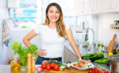 Obraz na płótnie Canvas Positive woman with vegetables at kitchen top