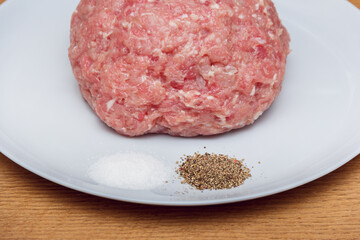 Minced pork on a plate with spec. Homemade meat semi-finished products. Minced pork. Semi-finished products for storage in the refrigerator