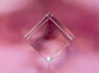 Transparent glass cube on a pink background