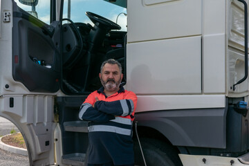 Truck driver posing next to the truck cab with the door open