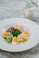 ingredients for cooking russian okroshka dish in a white plate on a marble table