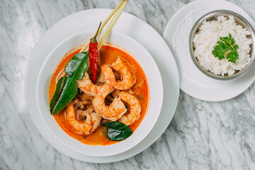 tom yum with shrimp and rice in a white plate on a marble table