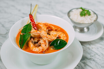 tom yum with shrimp and rice in a white plate on a marble table