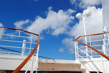 Open deck of a cruise ship, with blue skies and white clouds in the background