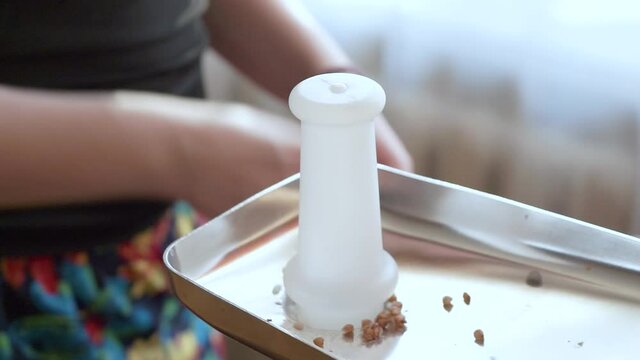 We prepare minced buckwheat groats with a meat grinder at home. Electric meat grinder with cereals. Cooking minced buckwheat with an electric meat grinder.A woman adds a tablespoon of minced meat to