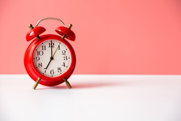 Alarm clock on a table on a pink background