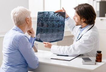 Doctor examining head x-ray scans of senior female patient
