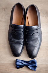 black stylish leather shoes and a blue butterfly on a wooden floor. groom's morning. gentleman's accessories.