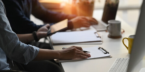 Cropped image of business people is working together with a computer laptop and tablet at the...