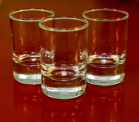 Three glass glasses on a red table closeup