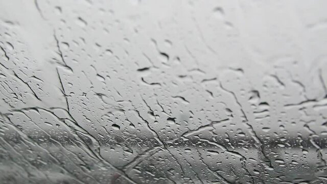 Raindrops on the windshield swipe by car swiper during heavy rain on traffic. 