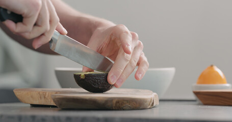 Man cutting ripe avocado into quarters and peel it on kitchen countertop side view