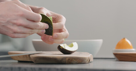 Man peel ripe avocado on kitchen countertop side view