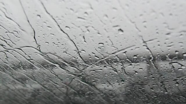 Raindrops on the windshield swipe by car swiper during heavy rain on traffic. 