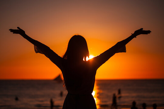 Woman raising arms to sunset