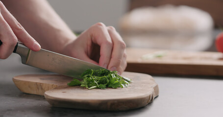 man chopping fresh parsley on olive board side view