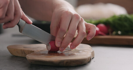 man cutting fresh radish on olive board side view