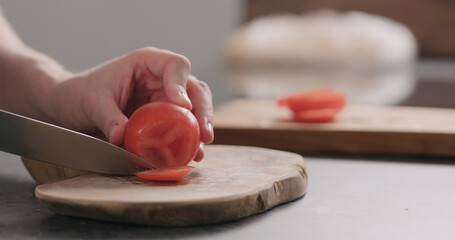 Man cutting tomatoe on concrete countertop side view