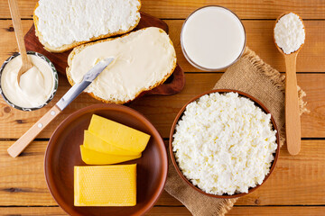 Various dairy products. Milk, cottage cheese, hard cheese and sour cream in a rustic style. Bread with cream cheese on a wooden boards. Top view