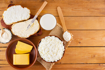 Various dairy products. Milk, cottage cheese, hard cheese and sour cream in a rustic style. Bread with cream cheese on a wooden boards. Top view