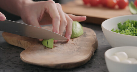 Obraz na płótnie Canvas Man slicing ripe avocado on kitchen countertop