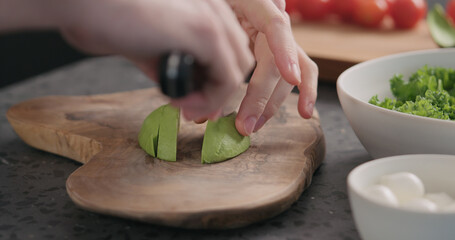 Man slicing ripe avocado on kitchen countertop