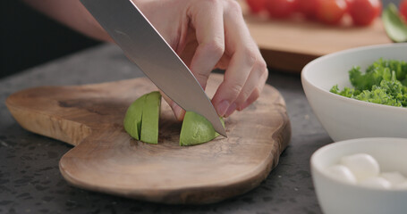 Man slicing ripe avocado on kitchen countertop