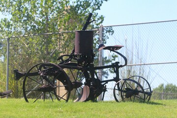Vintage vehicle with rusty wheels displayed inside a grassy area