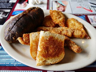 Plate with big oven roasted potato, toasted bread and fried chicken strips