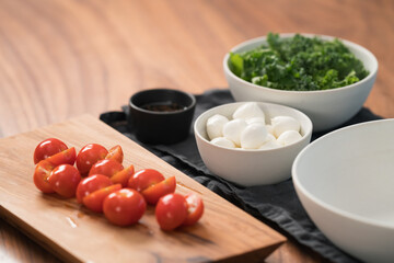 ingredients and empty white bowl on walnut table