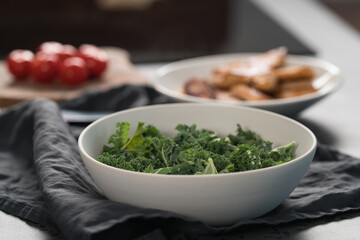 kale salad leaves in white bowl on linen napkin with other ingredients on background