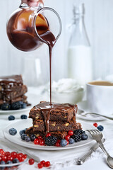 Tempting homemade brownie with chocolate sauce and berries on white plate. Delicious dessert.