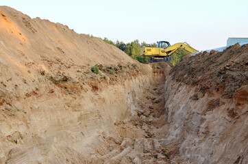 Excavator digs ground for the installation of industrial gas and oil pipes. Natural gas pipeline construction work. A dug trench in the ground. Backhoe the digging pipeline ditch.