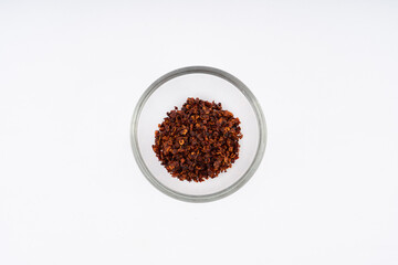 Chilli, red chilli flakes, dried chillies flakes in glass cup on a white background 