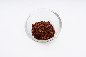 Chilli, red chilli flakes, dried chillies flakes in glass cup on a white background 