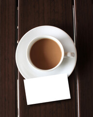 cup of coffee with blank card on wooden table
