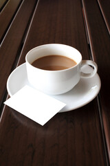 cup of coffee with blank card on wooden table