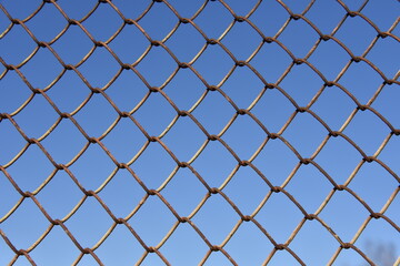 Metallic fence net against the sky