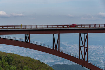 つばくろ谷からみる不動沢橋を走る赤い車
