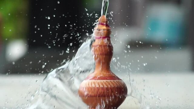 Handmade traditional craft known as 'labu sayong' pouring with water. Used as gift or souvenir found in Perak,Malaysia. Clay pottery arts.