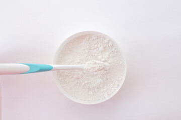 close-up of tooth powder in a jar and a toothbrush on a white background. text space, top view, layout