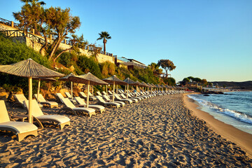 empty sunbeds and umbrellas on a sandy beach waiting for tourists on Zakynthos island in Greece..