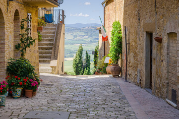 Sunny streets with colorful flowers with contrasting shades. Walk the Tuscan town - 355837271