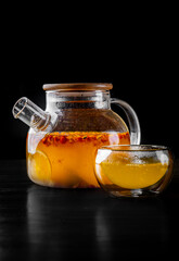 tea pot and Cup of sea buckthorn tea on black background