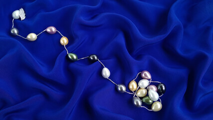 Multi colored pearl necklace is beautifully laid out   on dark blue silk.  Iridescent big   natural...