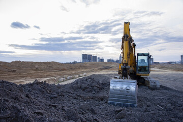 Excavator work at constrruction site on sunset background. Backhoe digs gravel and old concrete....